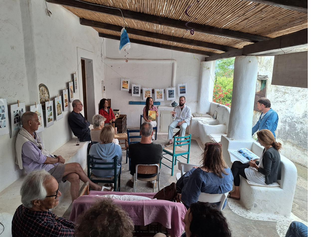 Presentazione di un libro sotto un pergolato con il pubblico seduto
