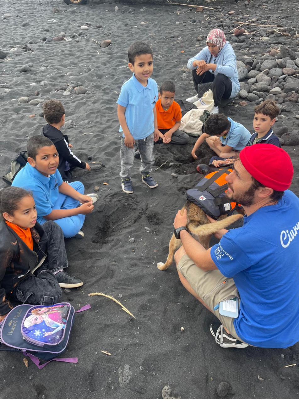 Bambini seduti sulla spiaggia nera vulcanica durante un'attività all'aperto